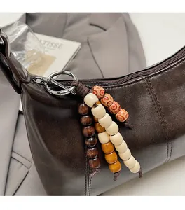 Detail of dark brown leather shoulder bag featuring decorative three-color wooden beads