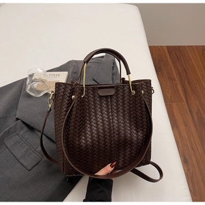 Detail of dark brown woven handbag with metallic round handle and texture