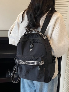 Modern black nylon backpack with lettered straps shown from a stylish back perspective