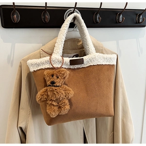 Close-up of brown suede tote bag with white faux shearling trim and cute bear charm