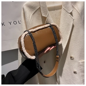 Close-up of brown patent leather bag with white plush trim and silver chain strap