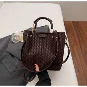 Detail of dark brown woven PU leather bucket bag with top handle and golden hardware