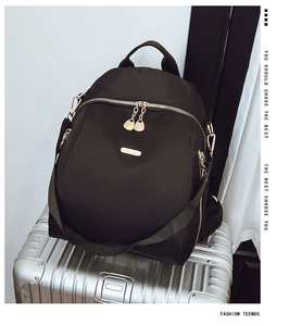 Close-up of black nylon backpack with golden logo plate on a silver suitcase