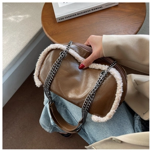 Detailed close-up of brown glossy leather crossbody bag with white faux fur trim and silver chain