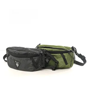 Detail of black and olive green techwear sling bags with white grid texture and brand label