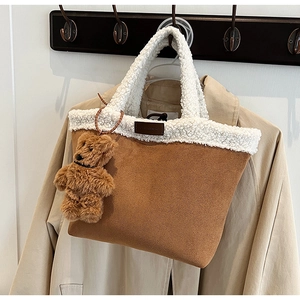 Detail of a brown faux suede tote bag with fleece trim and a cute plush bear charm