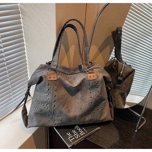 Détail du sac cabas gris foncé avec clous argentés et poignées en cuir marron contrastées