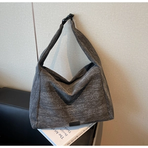 Close-up of textured grey tote bag with buckle strap on a minimalist background