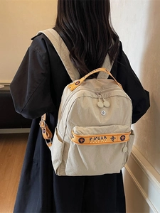 Minimalist beige nylon fashion backpack with orange jacquard straps shown from behind