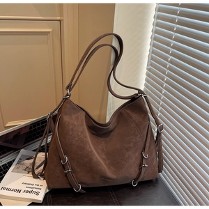 Detail of dark brown tote bag with multi-buckle straps and soft suede-like texture