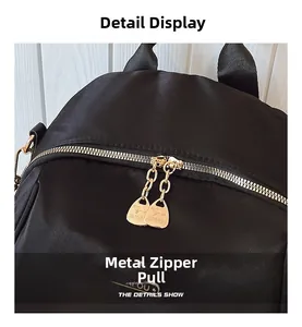 Detail shot of golden dual zippers with logo on black Oxford fabric backpack