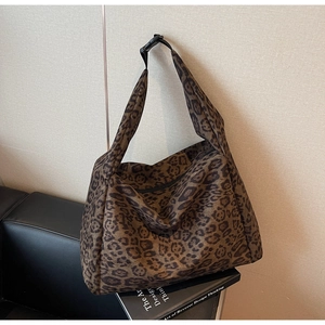 Detailed close-up of leopard print suede tote with adjustable black buckle and wide strap