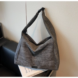 Detail of gray canvas tote bag with adjustable plastic buckle strap and leather base