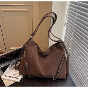 Detail of vintage brown tote bag featuring multi-strap design and metallic silver buckles