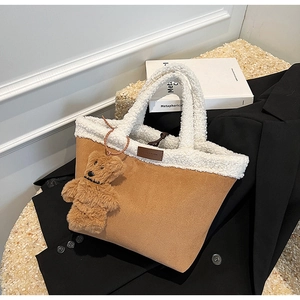 Detail view of brown suede tote bag with white faux fur trim and cute bear charm