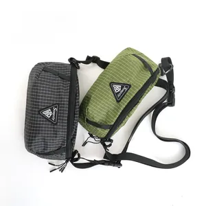 Flat lay of ripstop nylon crossbody bags in charcoal and olive green with logo