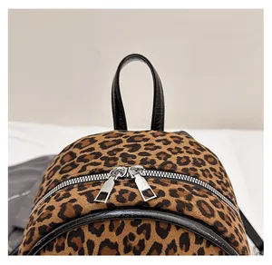 Détail d'un sac à dos léopard avec poignée en cuir robuste et fermeture éclair en métal