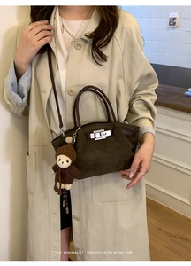 Detail of dark brown suede handbag with silver turn-lock and cute bear charm