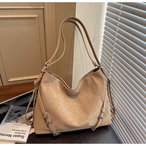 Detail of beige hobo bag with vintage texture and silver buckles on a leather surface