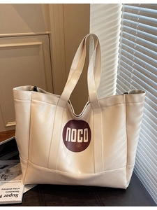 Minimalist creamy white leather tote bag with red circular NOCO logo in interior setting