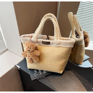 Detail of fuzzy faux shearling trim on khaki suede tote bag with cute bear charm