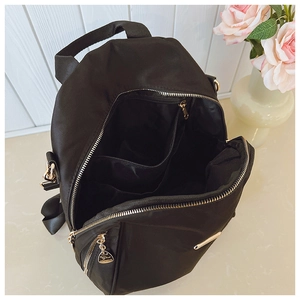 Detail view of large interior compartment and golden zippers on black nylon backpack