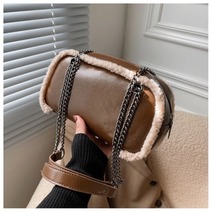 Detail of vintage brown leather cylinder bag with cream fleece trim and metal chain strap
