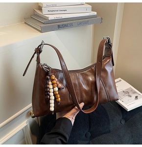 Detail of vintage brown leather dumpling bag featuring decorative wooden bead tassels and strap