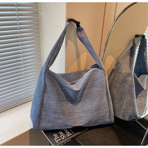 Detailed close-up of blue denim tote bag texture with wide adjustable shoulder strap