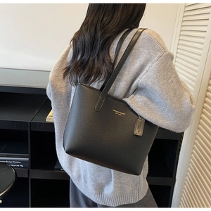 Détail montrant la texture du cuir noir et le logo doré sur un grand sac cabas chic