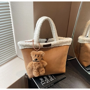 Detail of brown suede tote bag with white plush trim and a cute teddy bear charm
