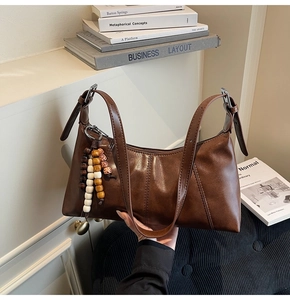 Detail of vintage brown leather shoulder bag with ethnic beaded charm and silver buckle