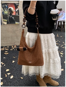 Détail du sac léopard avec bandoulière en perles de bois et lunettes dans la poche