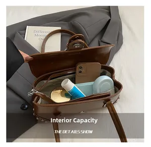 Vue détaillée de l'intérieur spacieux du sac rétro marron avec rivets et objets usuels