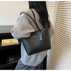 Sac cabas en cuir noir texturé porté à l'épaule avec logo doré et détails raffinés