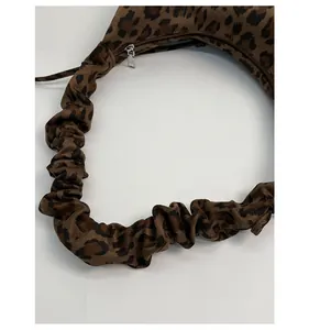 Detailed close-up of leopard print fabric texture and elastic ruched shoulder strap