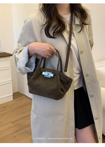 Close-up of minimalist retro bucket bag featuring silver twist lock and suede texture