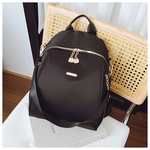 Detail of black oxford backpack featuring heart-shaped gold zippers and metallic logo
