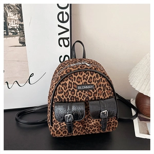 Vue détaillée du sac à dos léopard avec boucles métalliques et logo sur table noire