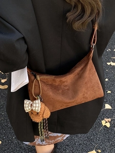 Sac à bandoulière en daim marron avec breloque ours en peluche sur l'épaule du mannequin