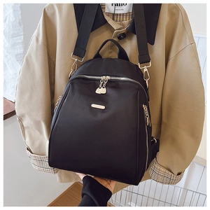 Detail of waterproof black nylon backpack with golden zippers and adjustable straps