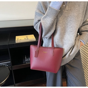 Détail du sac cabas bordeaux en cuir grainé avec logo doré et finition texturée fine
