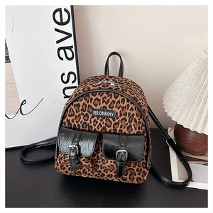 Détail du mini sac à dos léopard avec poches noires brillantes et plaque logo en métal