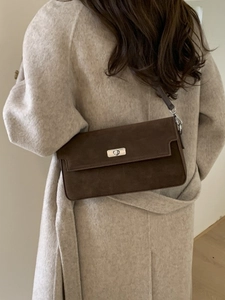 Vintage brown suede rectangular crossbody bag with silver buckle worn on a wool coat