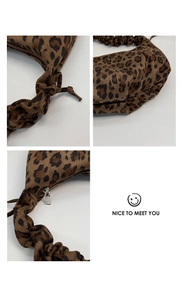 Detail of leopard print faux suede shoulder bag featuring pleated handle and metal zipper