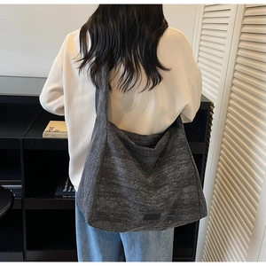 Detail of a large grey tote bag showing its minimalist canvas texture and wide strap