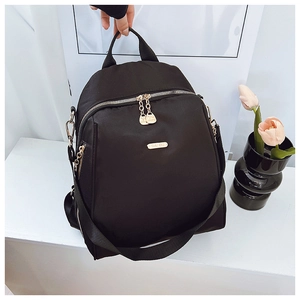 Close-up of black nylon backpack featuring gold metal brand logo and premium zipper