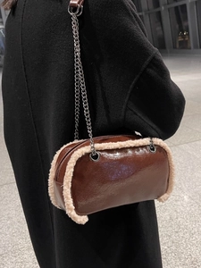 Brown patent leather crossbody bag with cream plush trim and chain strap shown on model