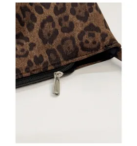 Macro detail of the smooth silver metal zipper and leopard print fabric on the handbag