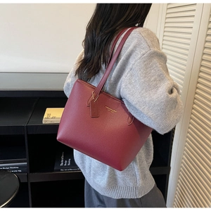 Détail du sac cabas en cuir grainé bordeaux avec logo doré et fines bandoulières élégantes
